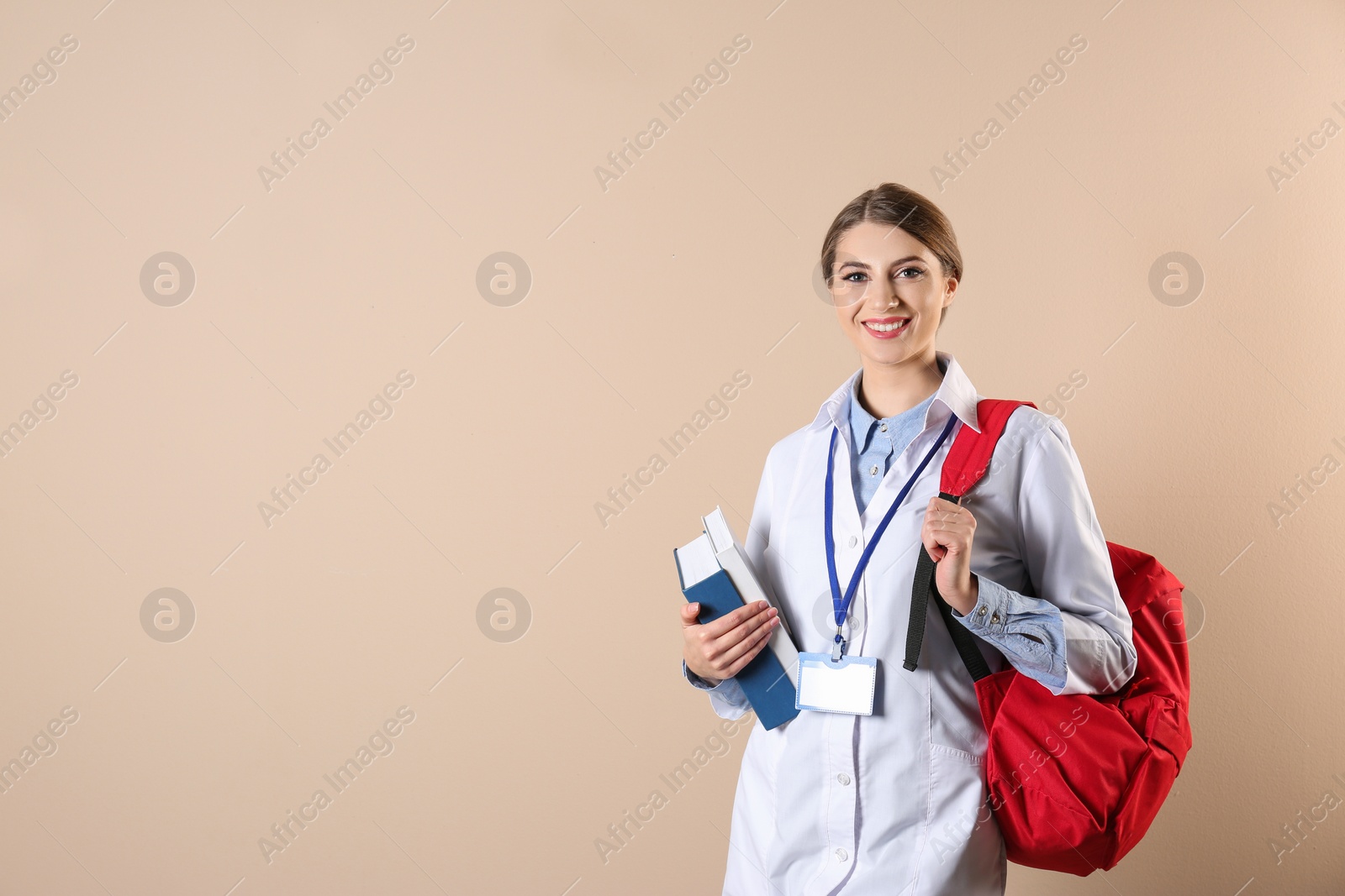 Photo of Young medical student with books and backpack on color background. Space for text