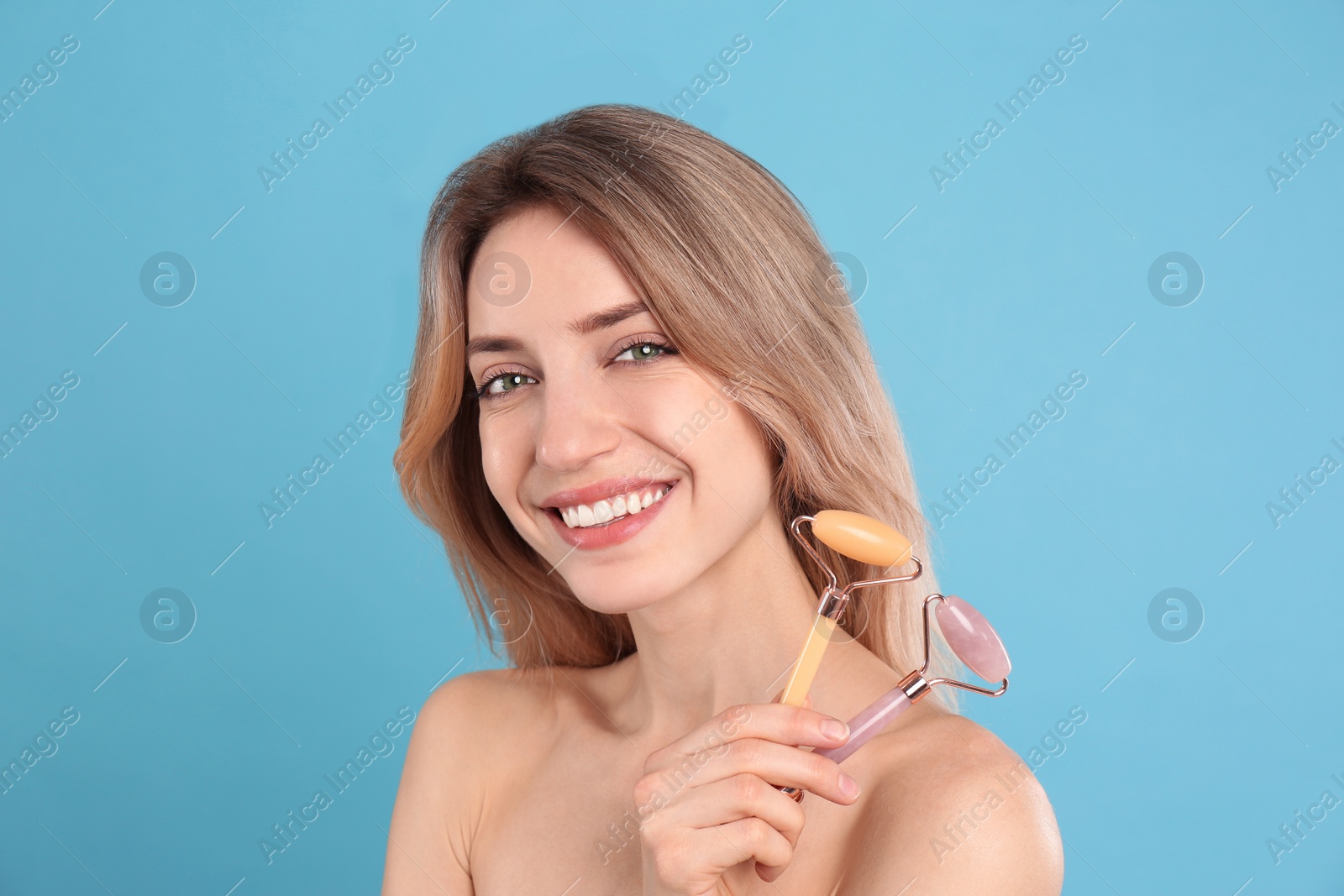 Photo of Young woman with natural face rollers on light blue background