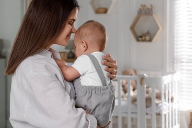 Photo of Happy young mother with her baby in nursery. Space for text