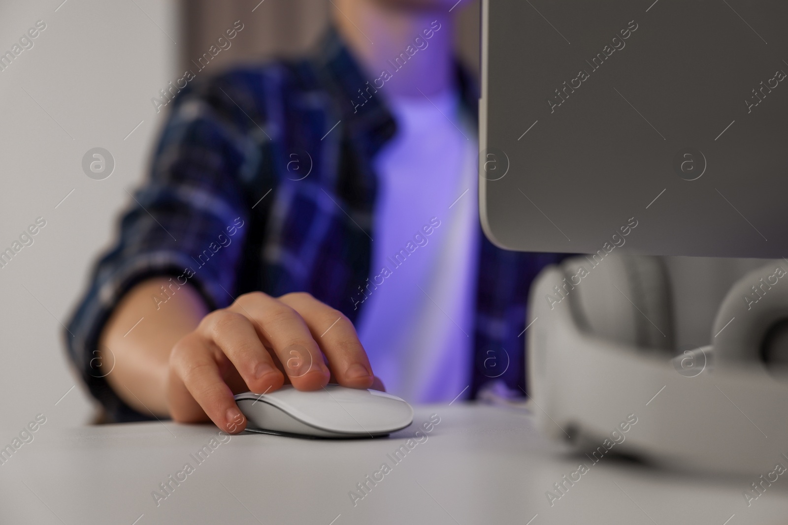 Photo of Teenage boy using computer in room at night, closeup. Internet addiction