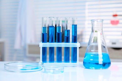 Photo of Laboratory analysis. Different glassware with blue liquid on white table indoors