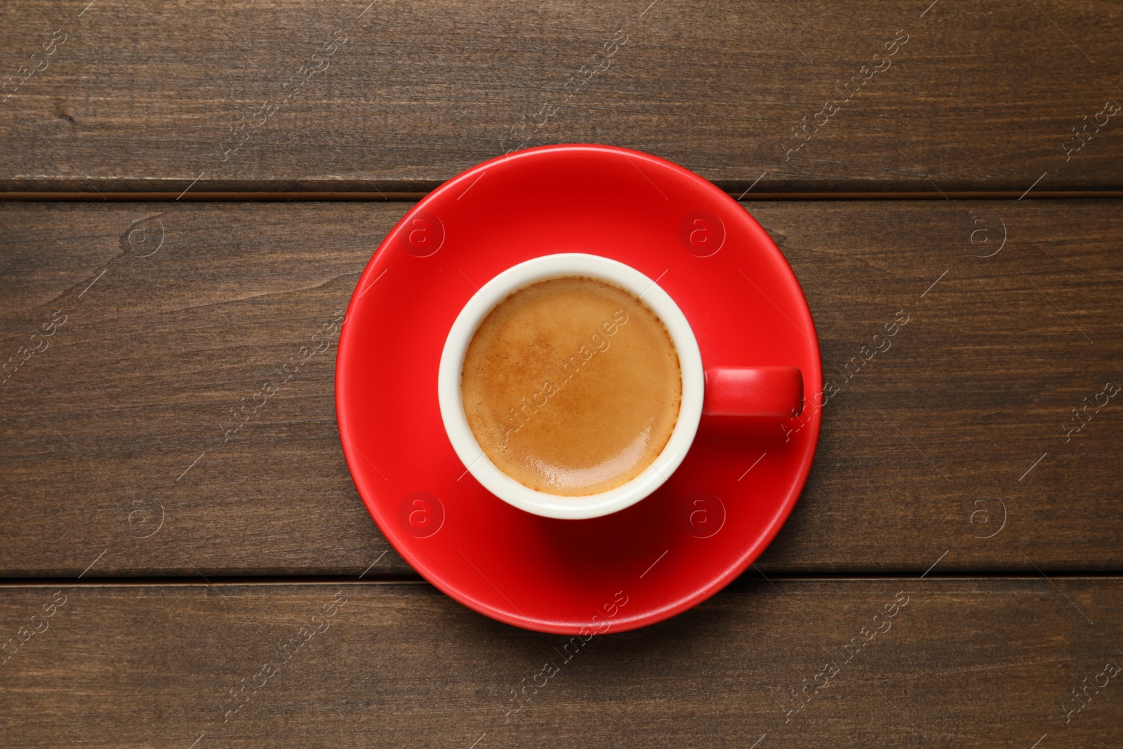 Photo of Aromatic coffee in red cup on wooden background, top view