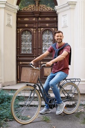 Handsome man with bicycle near ornate door on street