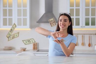 Photo of Young woman throwing money at table in kitchen