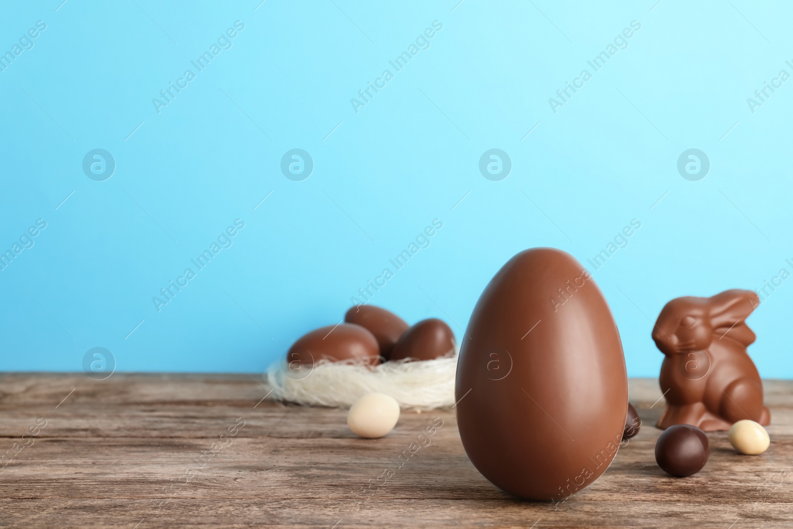 Photo of Beautiful composition with chocolate Easter egg on wooden table. Space for text