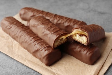 Photo of Sweet tasty chocolate bars with caramel on grey table, closeup