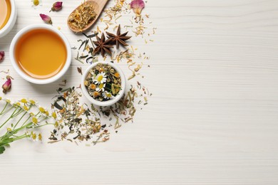 Flat lay composition with fresh brewed tea and dry leaves on white wooden table, space for text