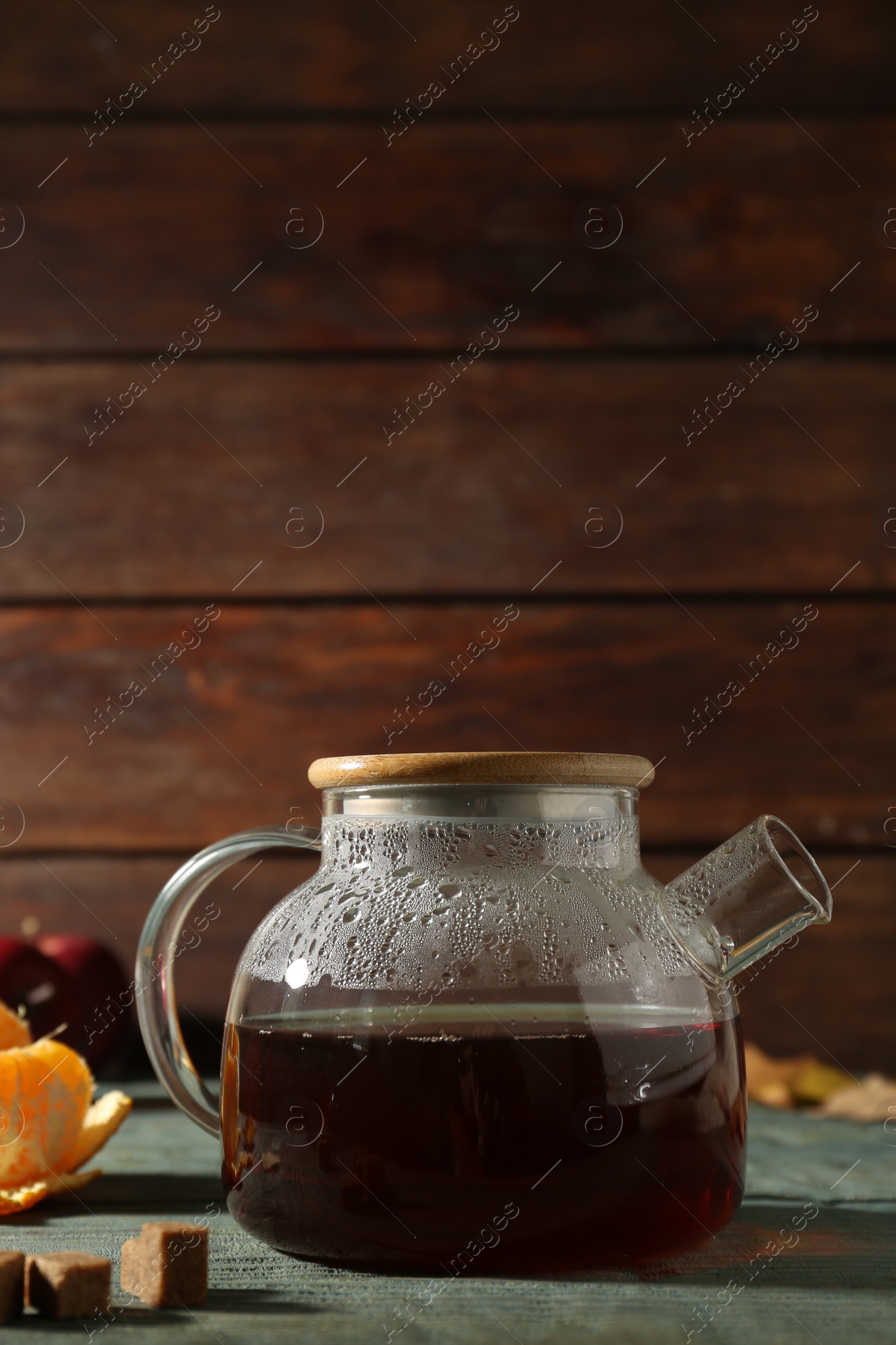 Photo of Glass teapot with hot beverage on light blue wooden table