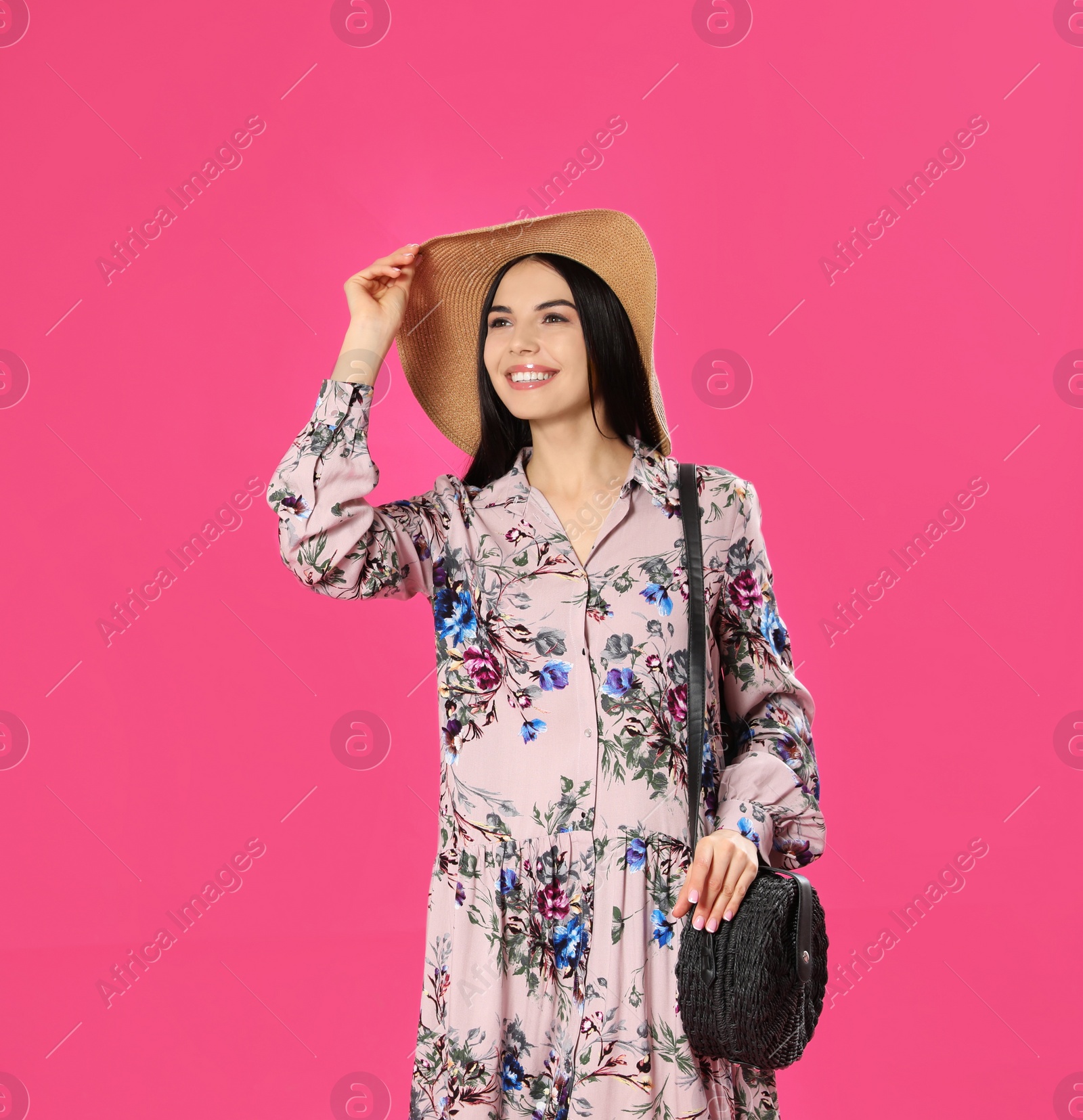 Photo of Young woman wearing floral print dress and straw hat on pink background. Space for text
