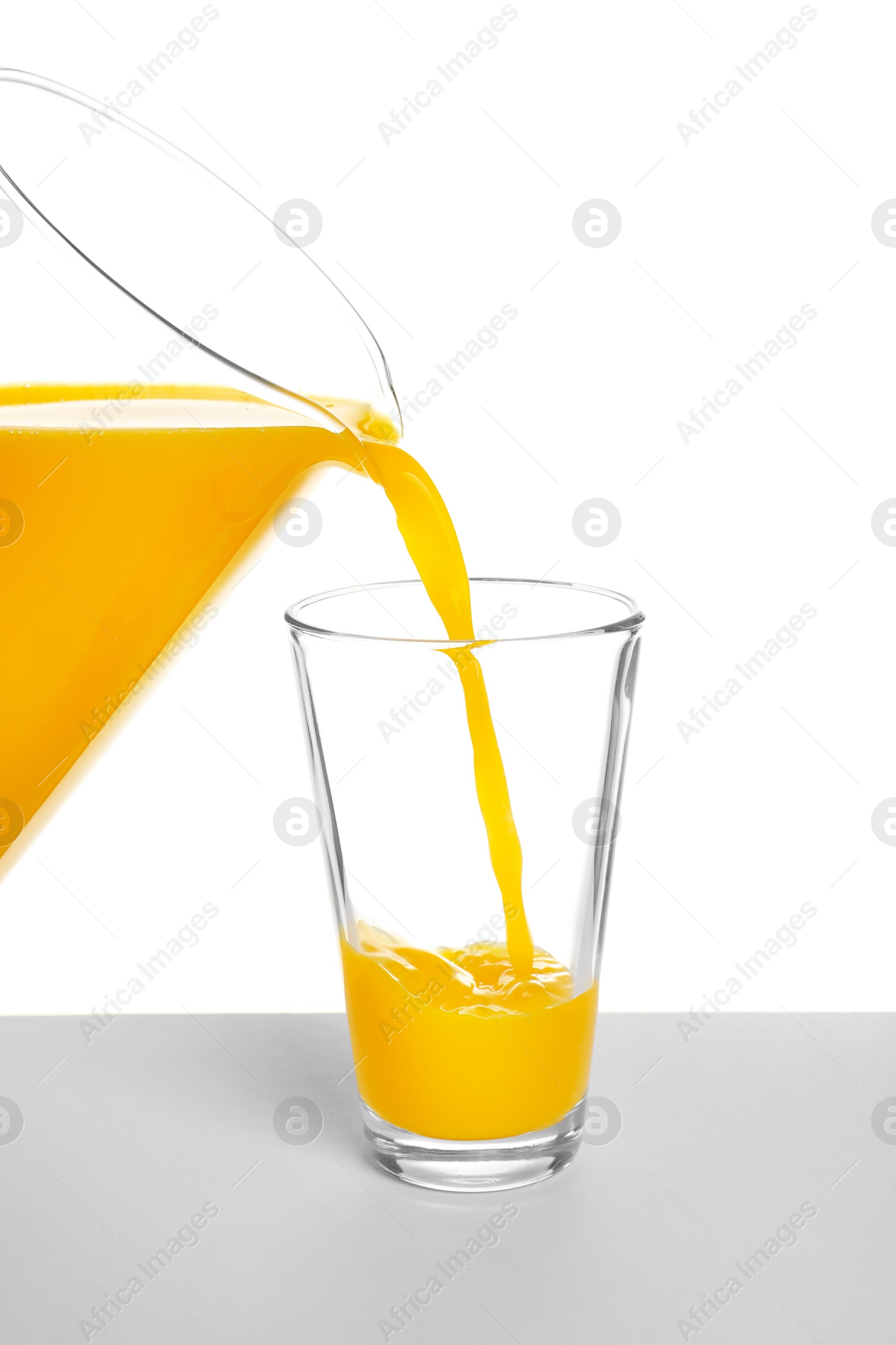 Photo of Pouring fresh orange juice into glass on white background