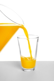 Photo of Pouring fresh orange juice into glass on white background