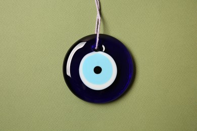 Evil eye amulet on olive background, top view