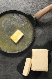 Photo of Melting butter in frying pan and dairy product on grey table, top view