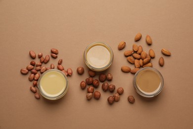 Photo of Different types of delicious nut butters and ingredients on brown background, flat lay