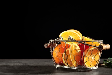 Photo of Fresh juicy oranges in basket on grey table. Space for text