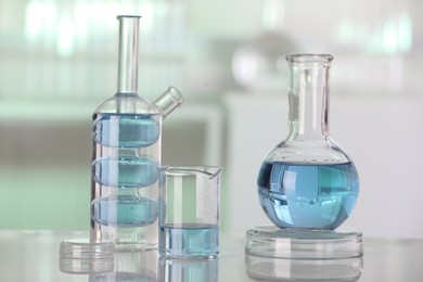 Photo of Laboratory analysis. Different glassware with liquid on white table against blurred background