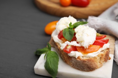 Photo of Delicious sandwich with burrata cheese and tomatoes on grey wooden table, closeup. Space for text