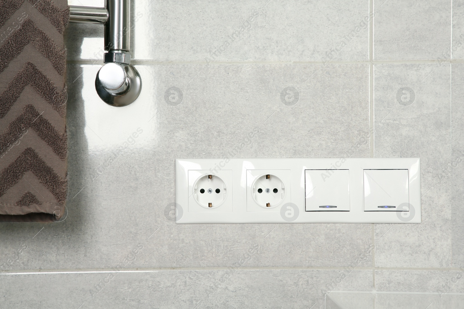 Photo of Light switches and power sockets on light grey wall in bathroom