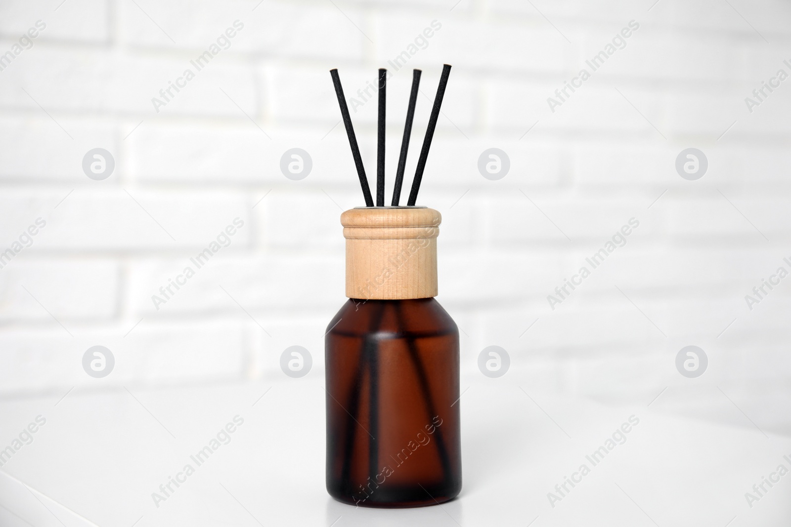 Photo of Reed diffuser on table near white brick wall, closeup