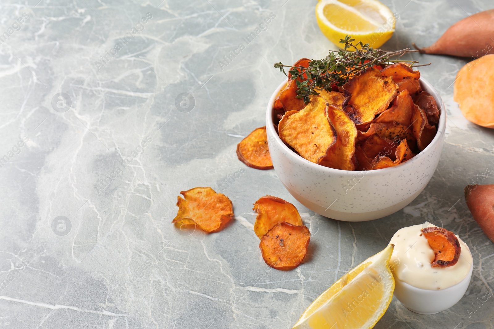 Photo of Composition with sweet potato chips and sauce on grey table. Space for text