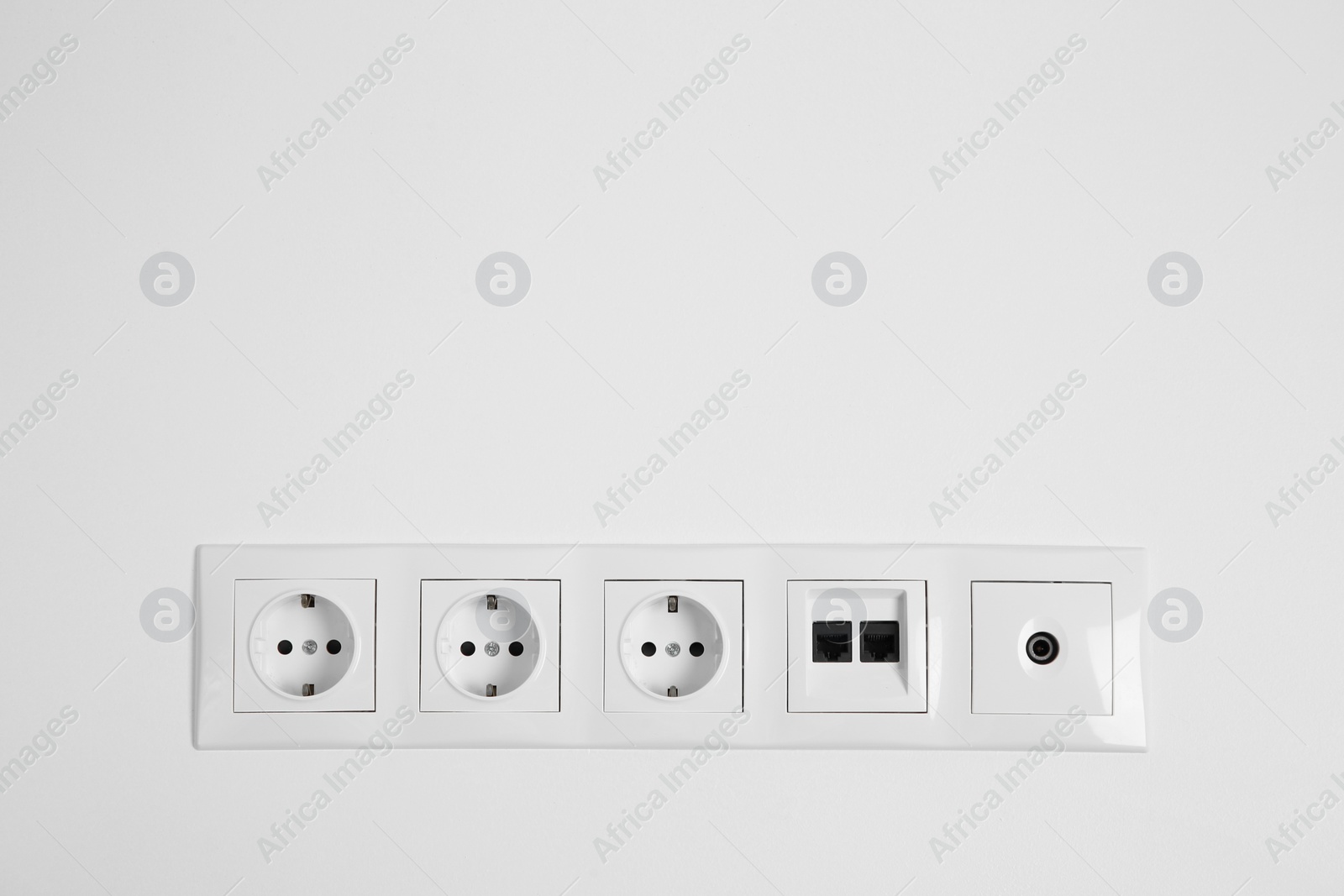 Photo of Many power sockets with ethernet and TV coax plates on white wall indoors. Space for text