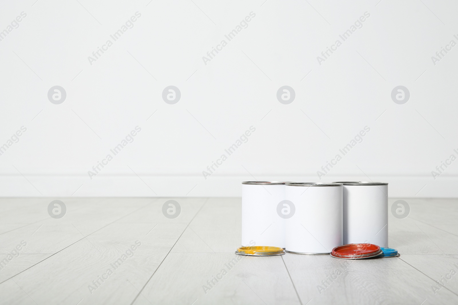 Photo of Cans of paint on wooden floor indoors. Space for text