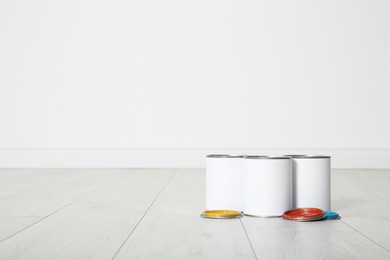 Photo of Cans of paint on wooden floor indoors. Space for text