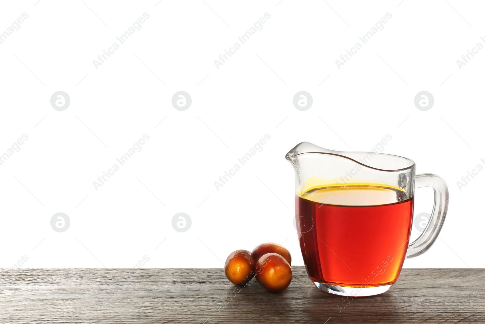 Image of Palm oil in glass jug and fruits on wooden table against white background