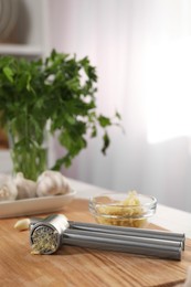 Garlic press and mince on wooden table in kitchen