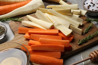 Raw parsnips, carrots and other products on light grey table