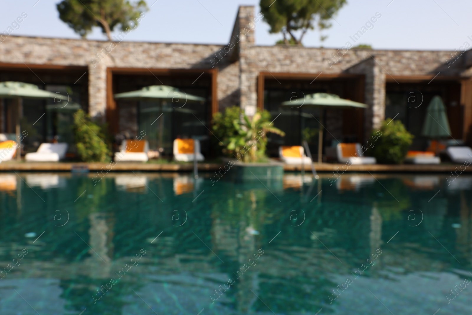 Photo of Blurred view of swimming pool, umbrellas and sunbeds at luxury resort