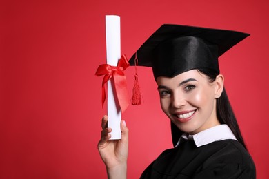 Photo of Happy student with graduation hat and diploma on red background. Space for text
