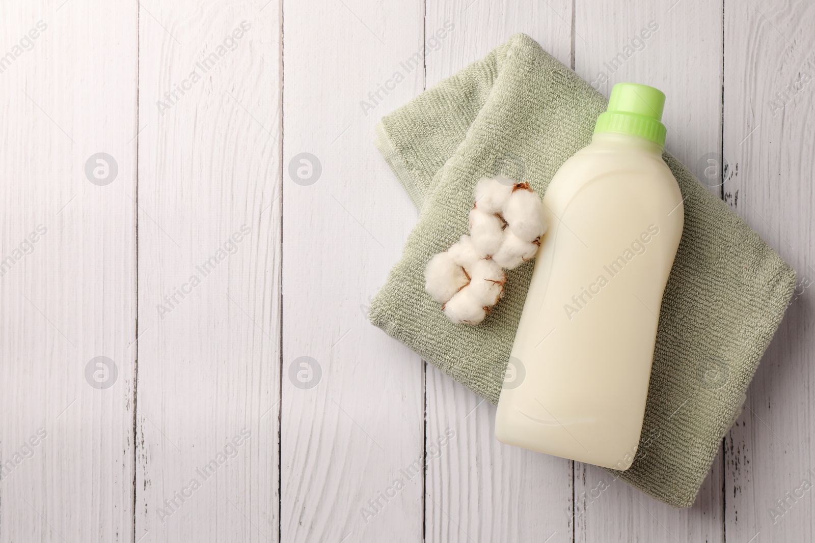 Bottle of fabric softener, terry towel and beautiful cotton flowers on white wooden surface, top view. Space for text Photo of Bottle of fabric softener, terry towel and beautiful cotton flowers on white wooden surface, top view. Space for text