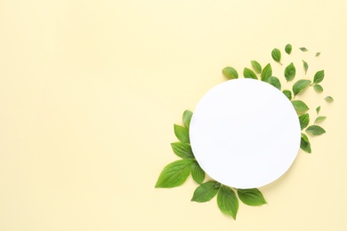 Photo of Flat lay composition with blank card and spring green leaves on color background. Space for text