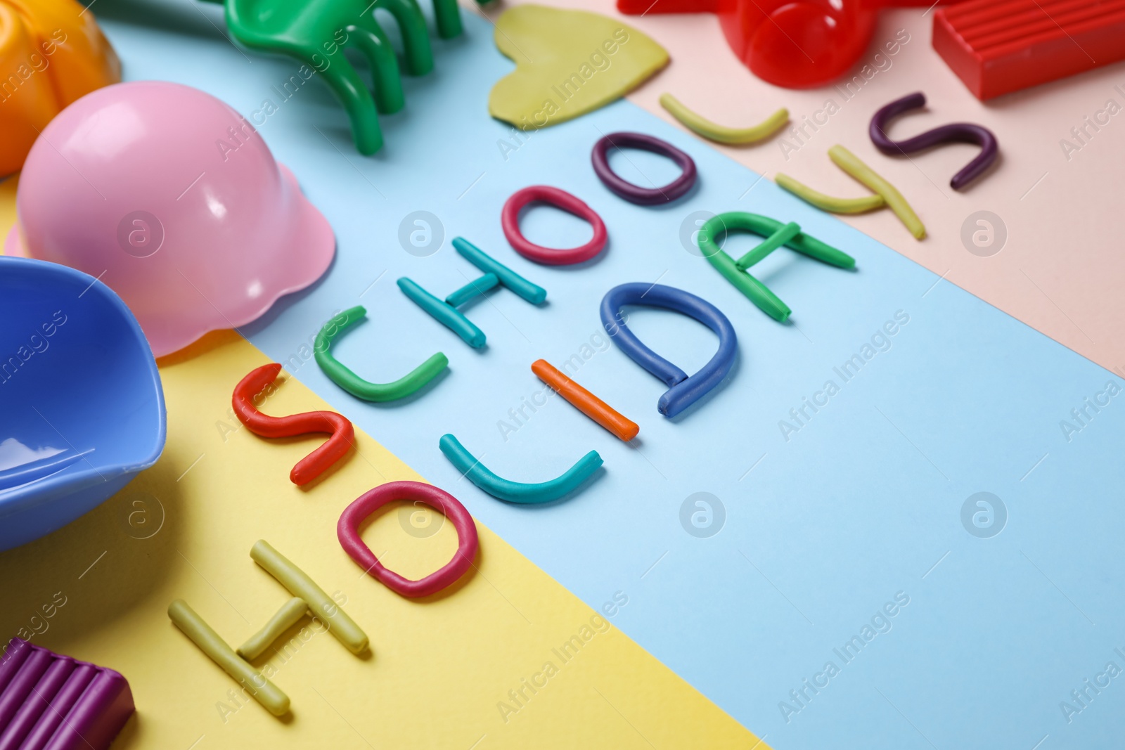 Photo of Composition with phrase School Holidays made of modeling clay on color background