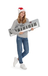 Photo of Young woman in Santa hat with synthesizer on white background. Christmas music