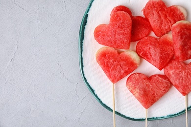 Photo of Plate with watermelon popsicles on grey background, top view