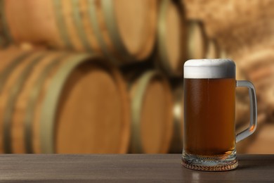 Image of Mug with fresh beer on wooden table in cellar, space for text