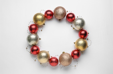 Beautiful festive wreath made of color Christmas balls on white background, top view