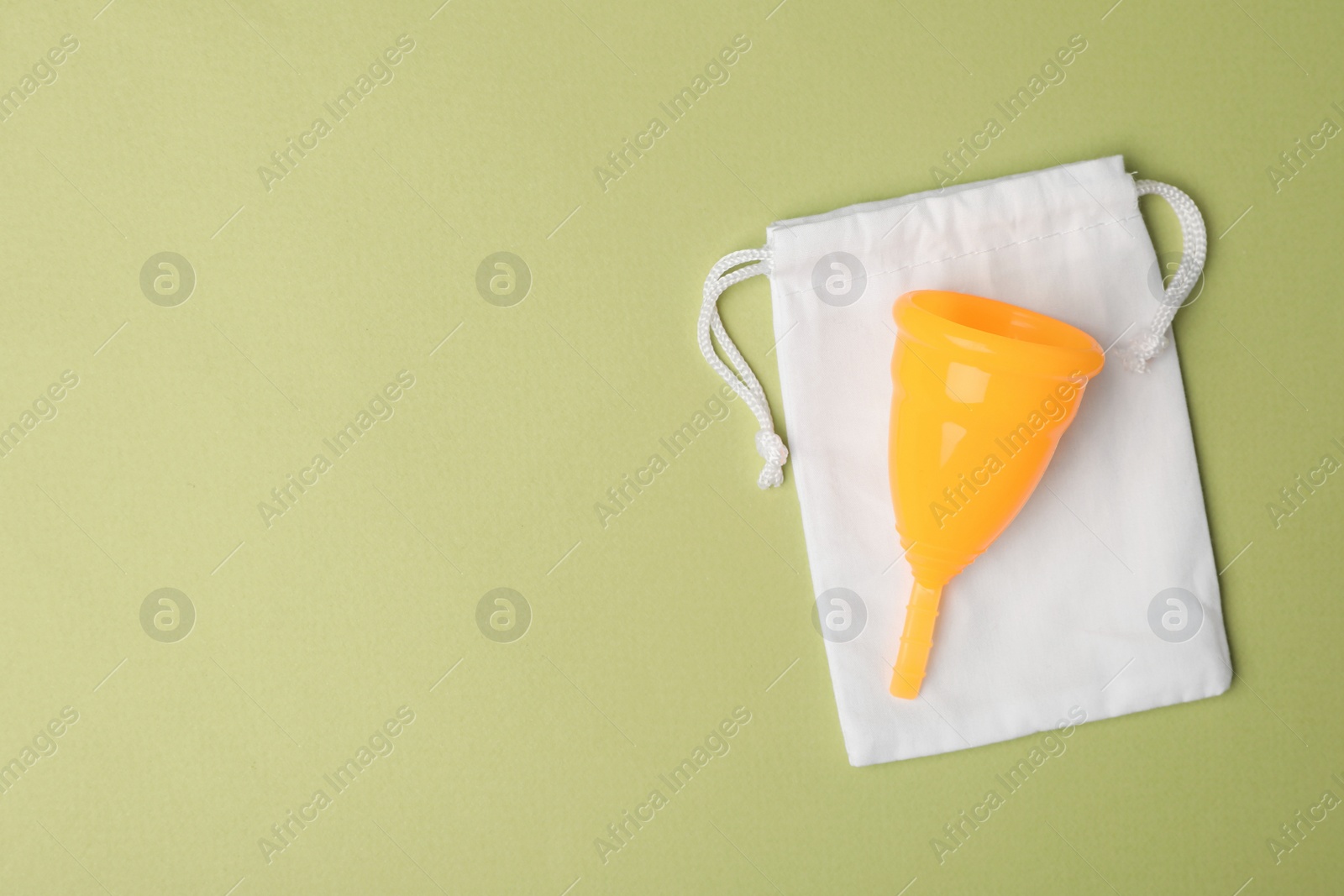Photo of Menstrual cup with bag on light green background, top view. Space for text