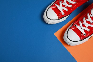 Photo of Pair of new stylish red sneakers on colorful background, flat lay. Space for text