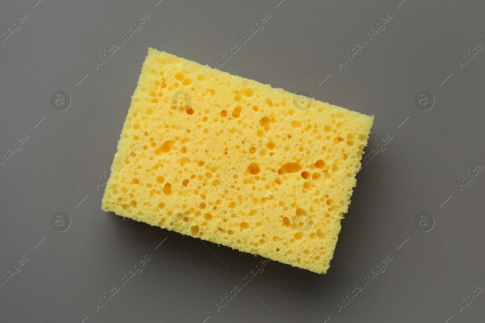 Photo of New yellow sponge on grey background, top view
