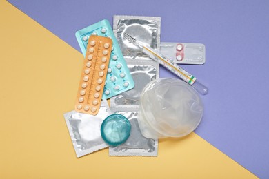 Photo of Contraceptive pills, condoms and thermometer on color background, flat lay. Choice of birth control method