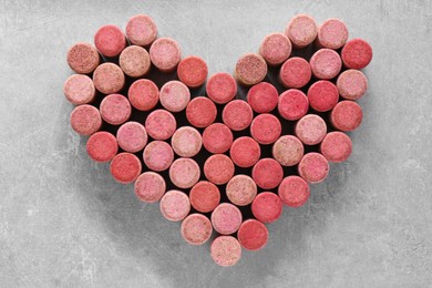 Photo of Heart made of wine bottle corks on grey table, top view