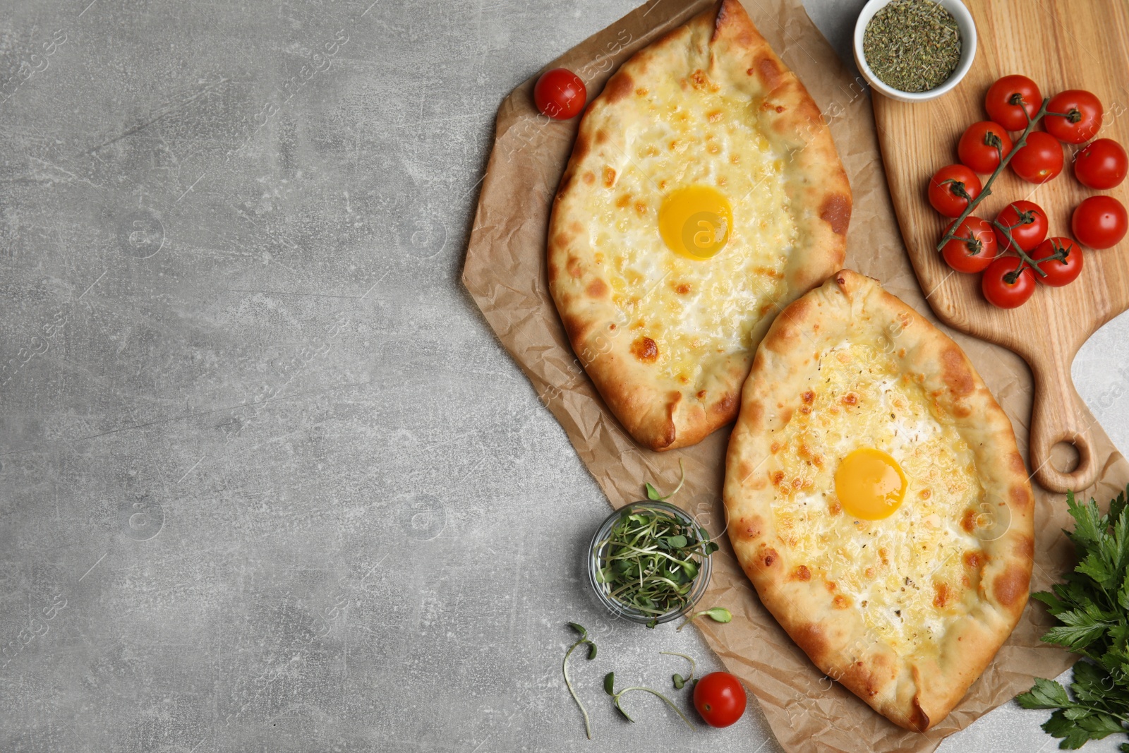 Photo of Fresh delicious Adjarian khachapuris served on grey table, flat lay. Space for text