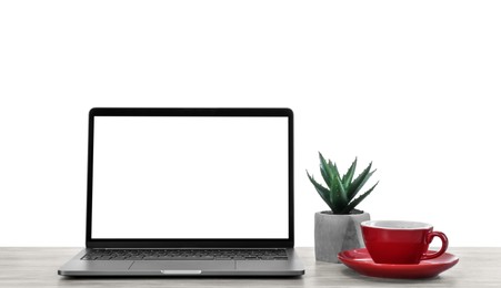New laptop with blank screen, cup of drink and potted plant on table against white background