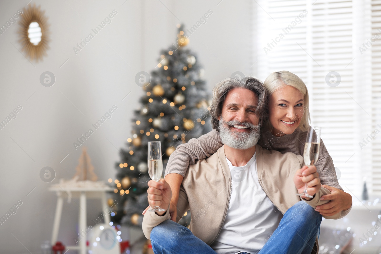 Photo of Happy mature couple with glasses of champagne celebrating Christmas at home