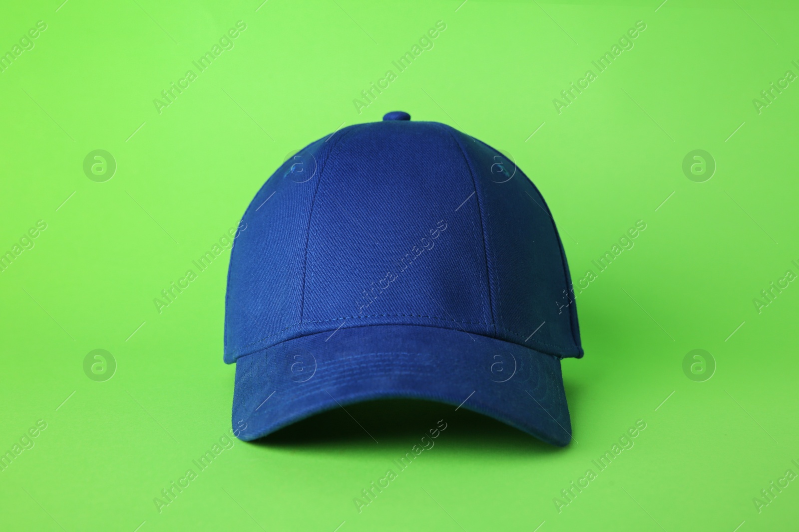 Photo of Stylish blue baseball cap on light green background