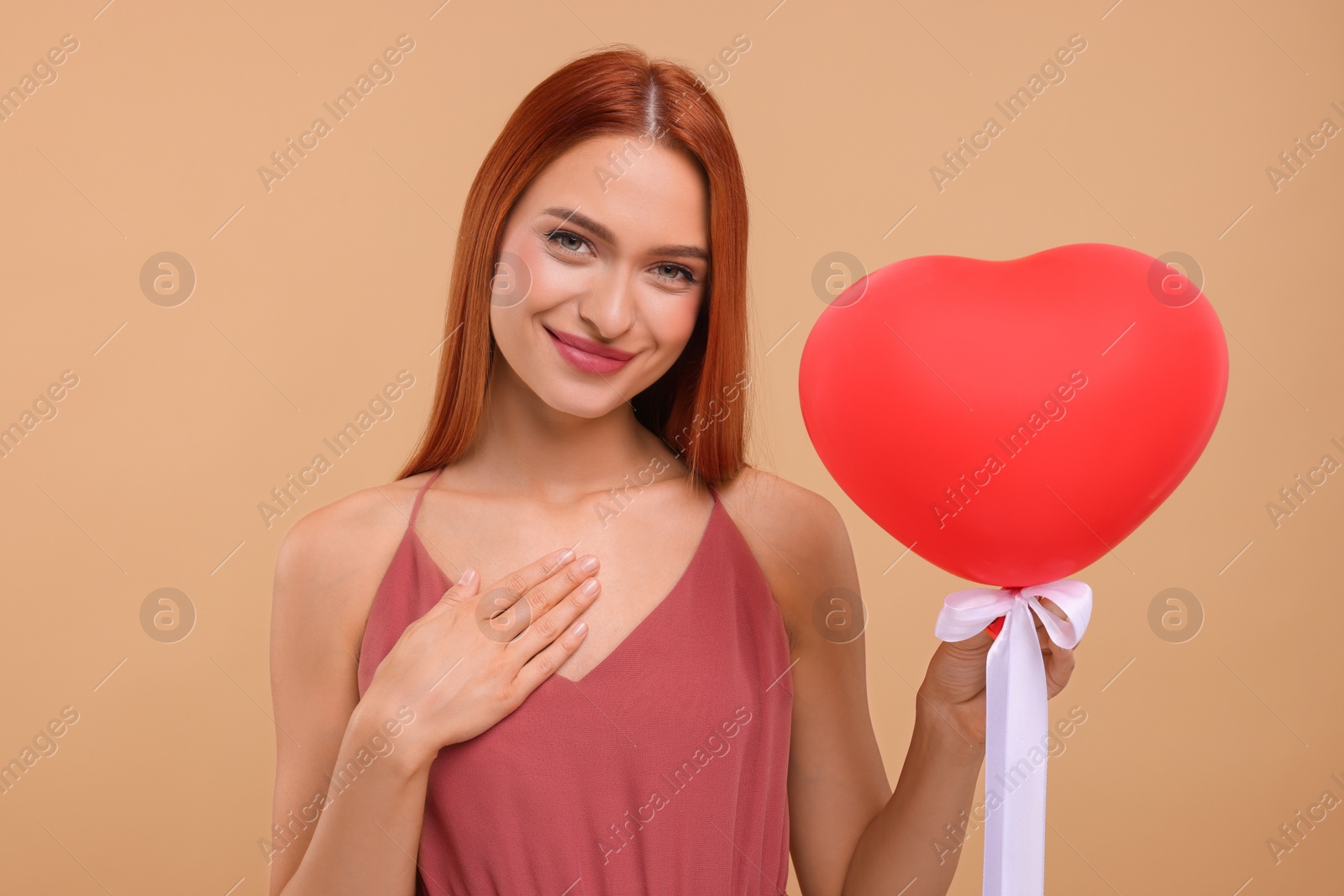 Photo of Beautiful woman with red heart shaped balloon on beige background