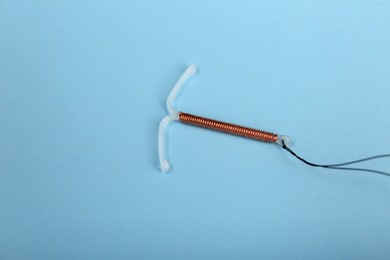 Photo of T-shaped intrauterine birth control device on light blue background